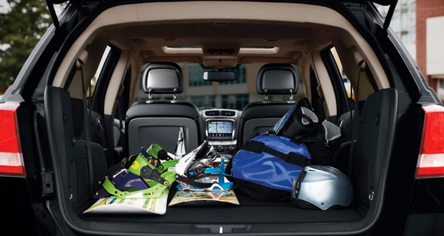 The rear cargo compartment of the 2020 Dodge Journey packed with snowboards, helmets and bags.