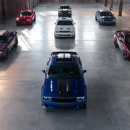 A warehouse with seven 2021 Dodge Challenger models, all with different exterior colors.