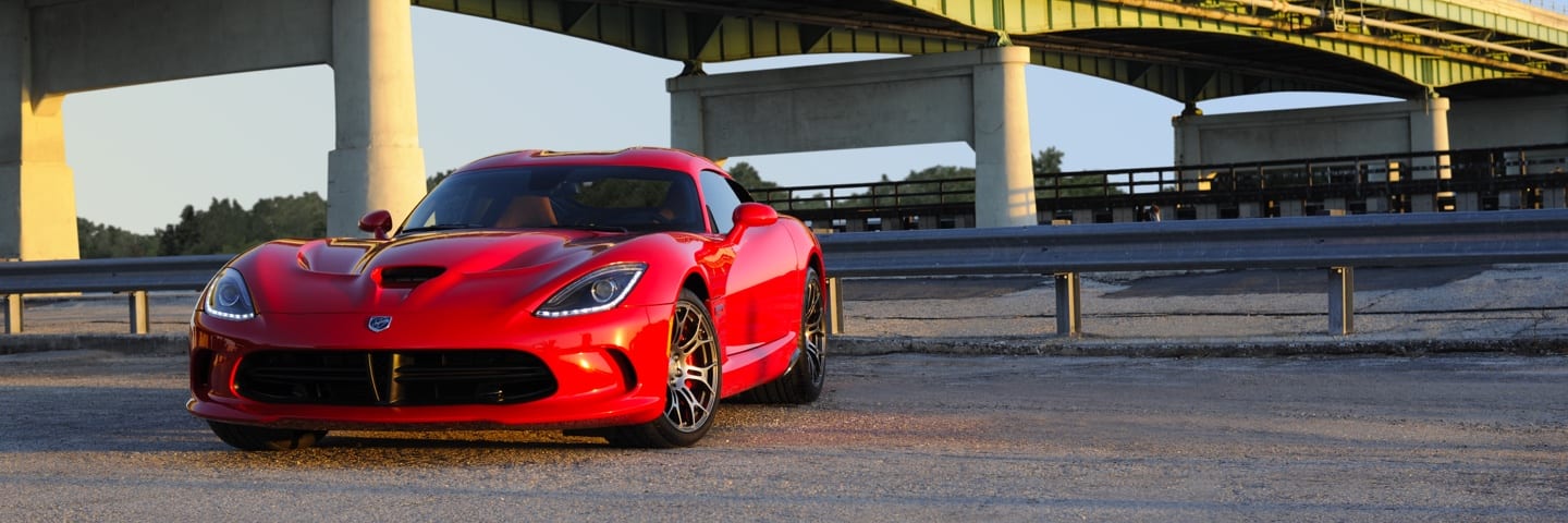 Three-quarter front profile view of a Dodge Viper parked on gravel under a bridge.