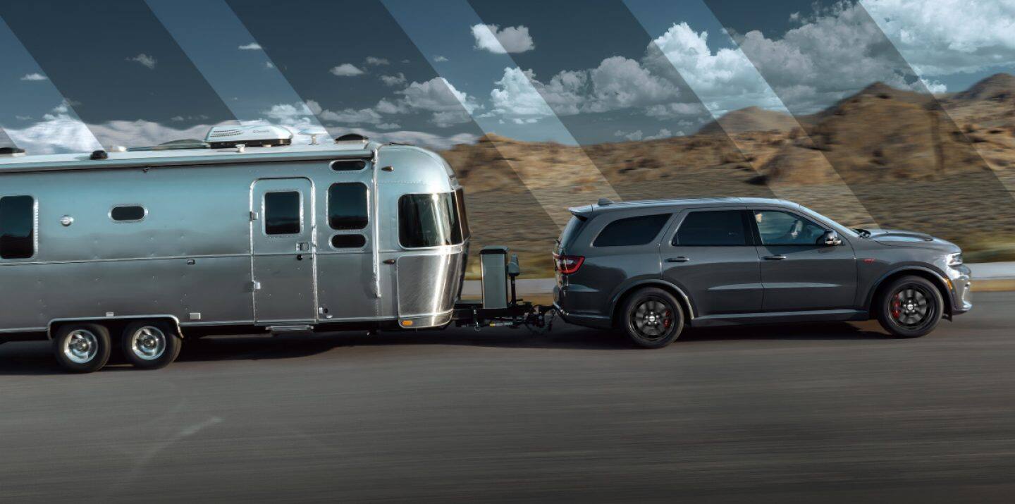The 2021 Dodge Durango R/T on a snowy track with a snowmobile in tow and gear attached to its roof rack.