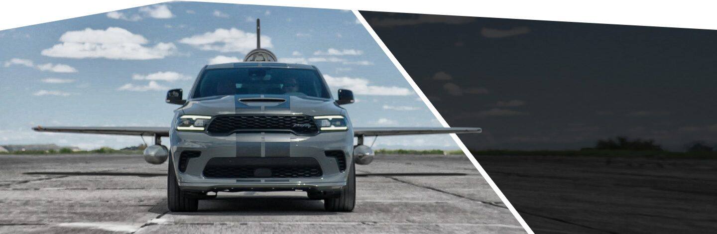 The 2022 Dodge Durango SRT parked in front of a small plane, its wings visible on either side of the vehicle.
