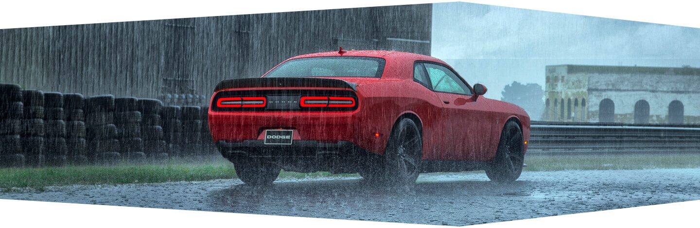 A three-quarter rear view of the 2020 Dodge Challenger being driven in a rainstorm.