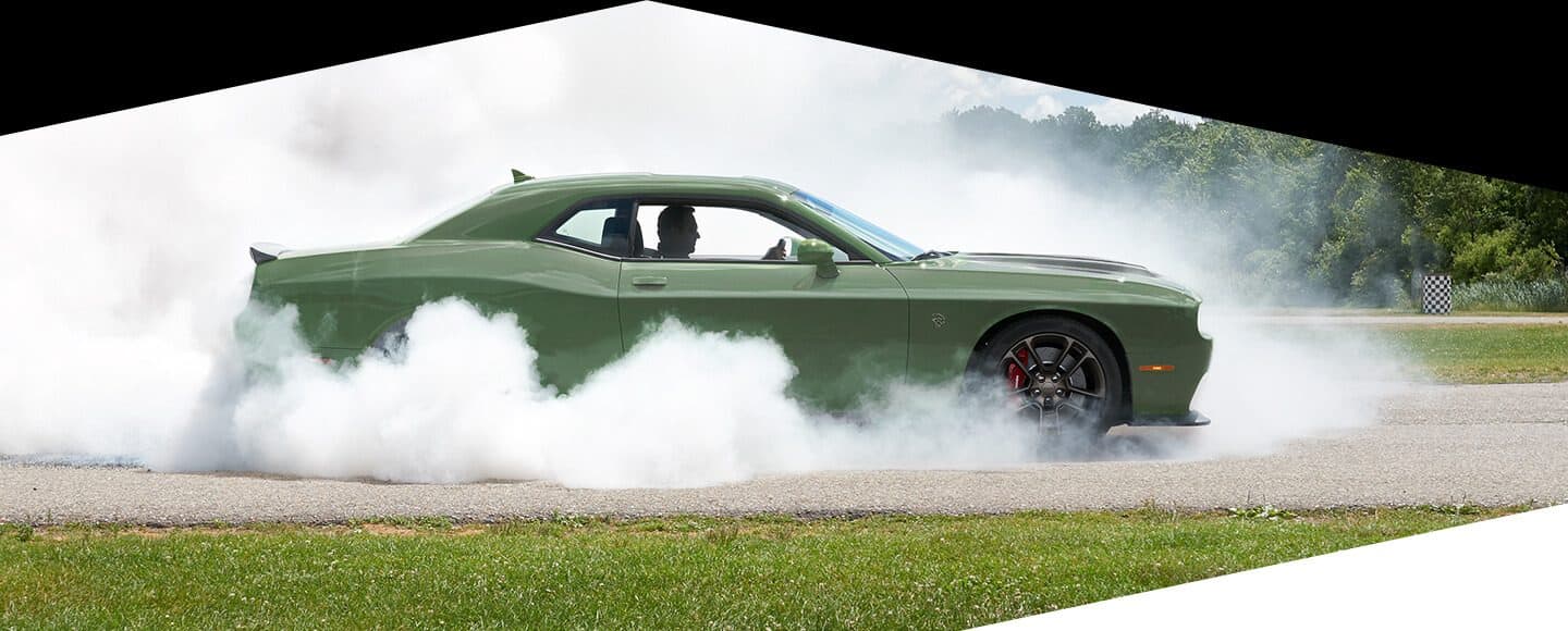 Profile view of a 2020 Dodge Challenger SRT Hellcat with smoke billowing from its rear tires.