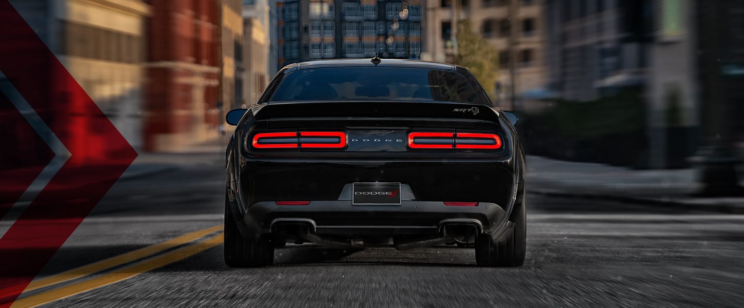 The rear of a black 2023 Dodge Challenger SRT Hellcat stopped on a city street with its taillamps on.