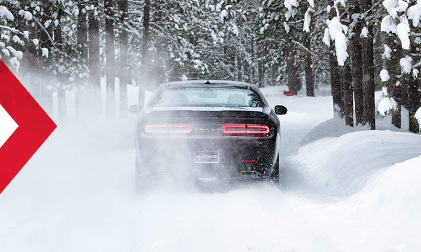 The rear of a 2023 Dodge Challenger SXT All-Wheel Drive, being driven through snow in the woods.