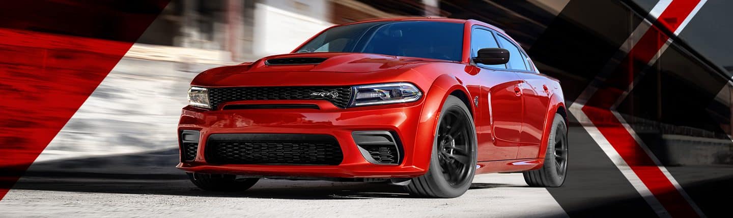 An angled front view of a red 2023 Dodge Charger SRT Hellcat Redeye with the background blurred to indicate the speed of the vehicle.