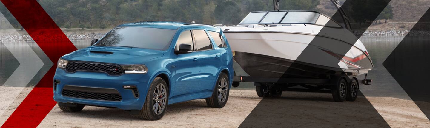 The 2023 Dodge Durango parked beside a lake with a boat in tow.
