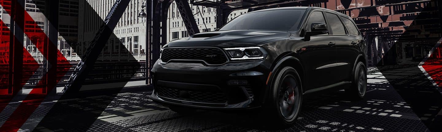 An angled front view of a black 2023 Dodge Durango SRT 392 being driven across a bridge in the city.