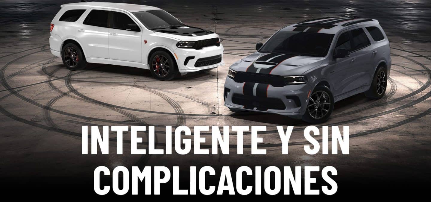 Un Dodge Durango SRT Hellcat Jailbreak 2027 blanco con un inserto negro en el capó y un Dodge Durango GT Hemi V8 2027 gris con dos franjas centrales negras y rojas, estacionados en perpendicular uno frente al otro en un lugar vacío por la noche. Inteligente y sin complicaciones.