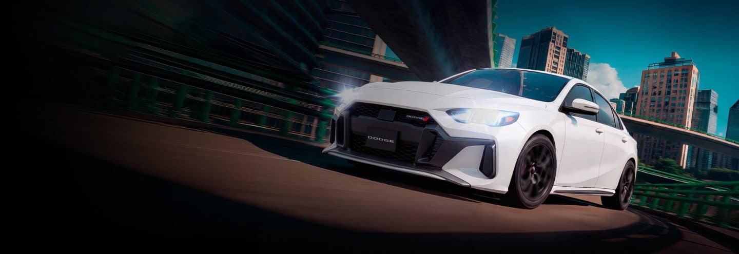 Dodge Attitude 2026 color blanco circulando a alta velocidad por la ciudad al atardecer