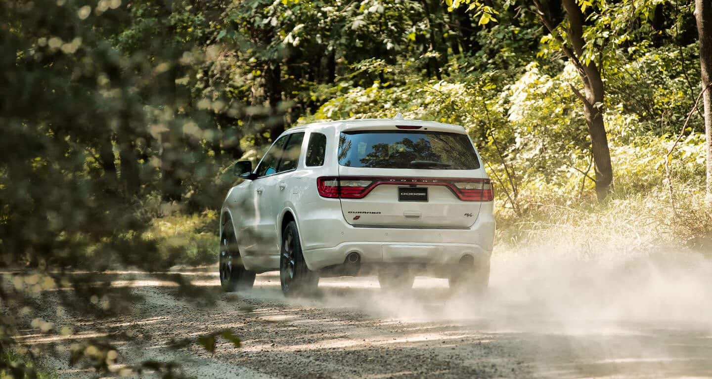 A three-quarter rear view of a 2020 Dodge Durango being driven on a dirt road.