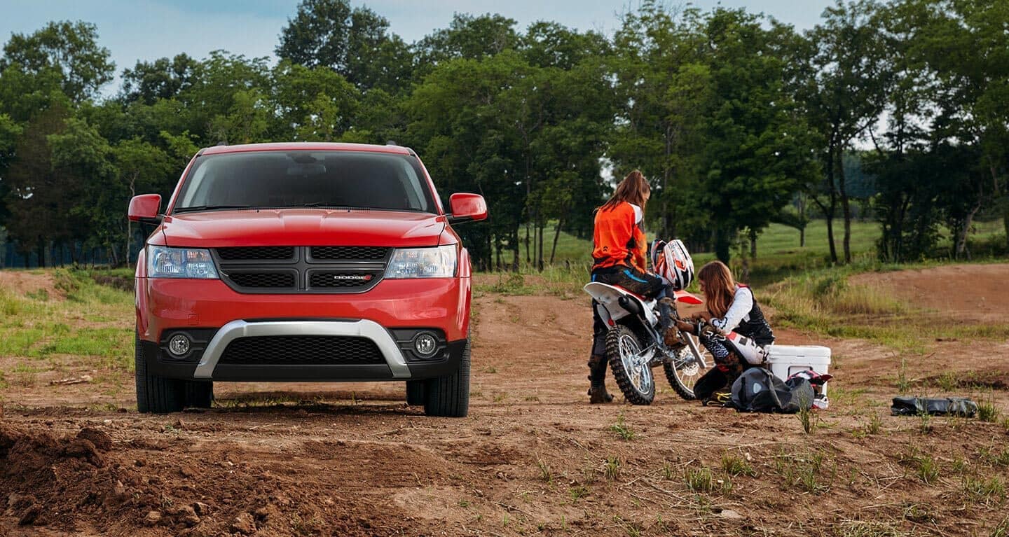 Display The 2020 Dodge Journey parked on a trail with two women working on a dirt bike beside it.