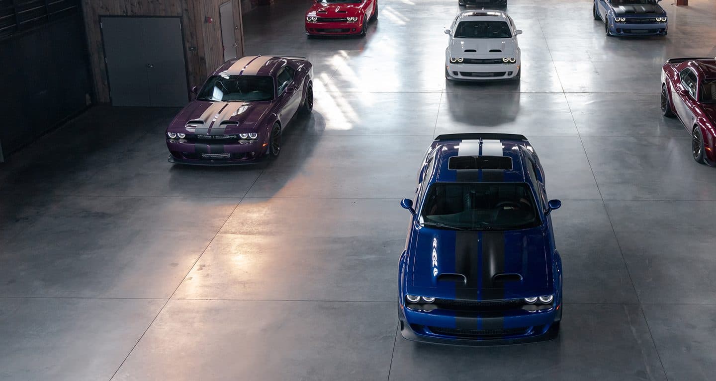 Display A warehouse with seven 2021 Dodge Challenger models, all with different exterior colors.