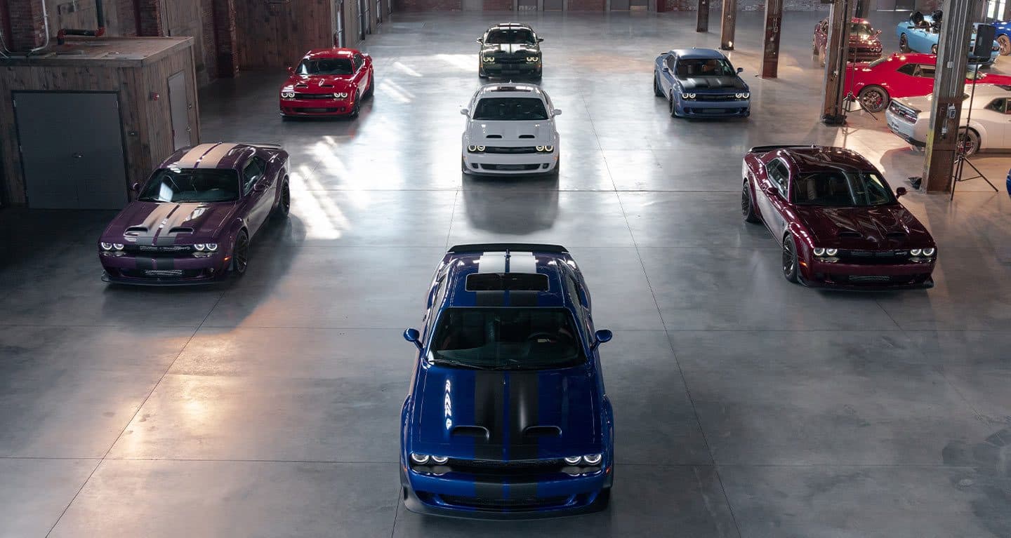 A warehouse with seven 2021 Dodge Challenger models, all with different exterior colors.