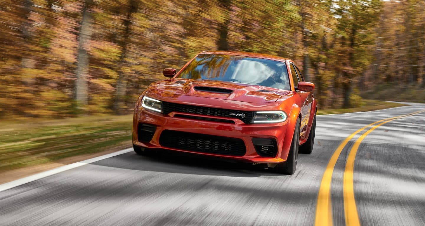 Display A 2022 Dodge Charger Scat Pack Widebody being driven on a winding country road.