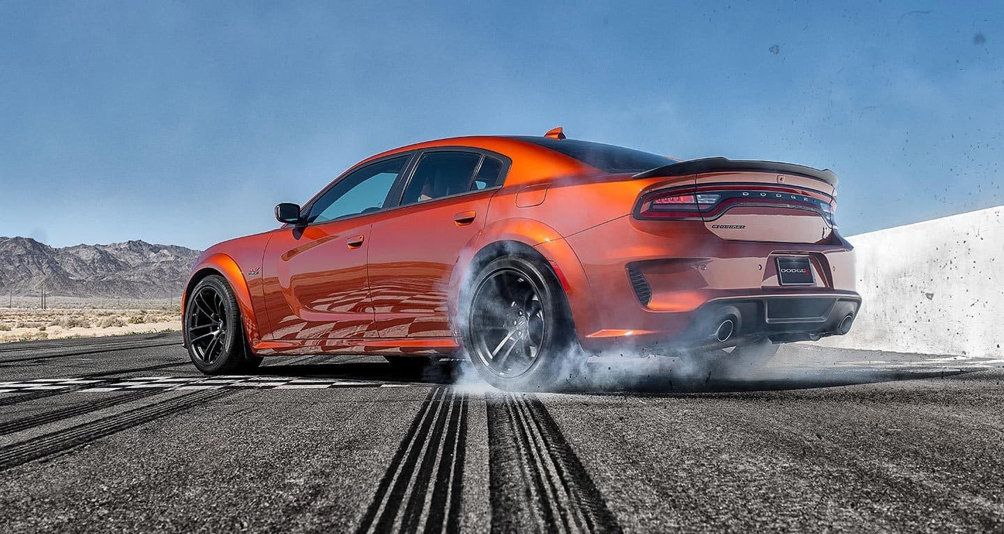 Display A 2022 Dodge Charger Scat Pack Widebody burning rubber on a track.