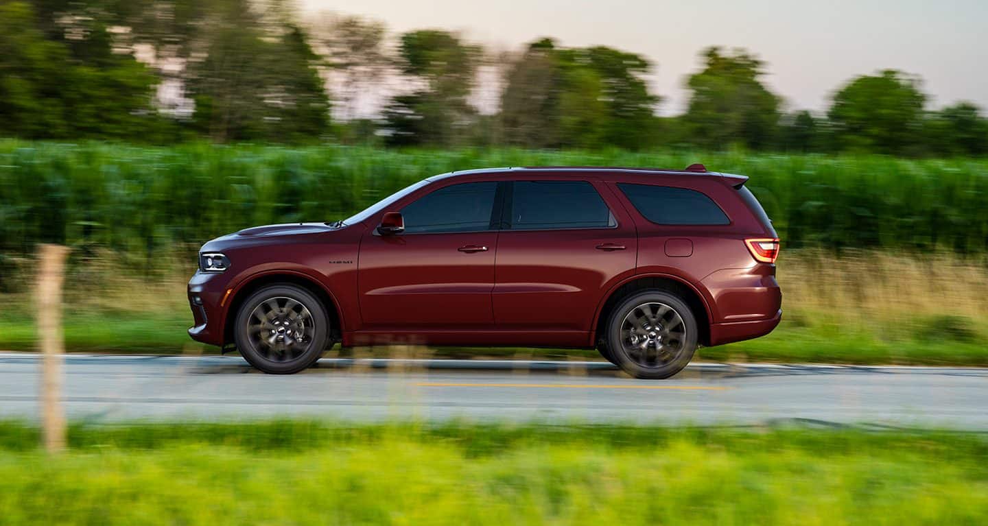 Display A driver-side profile view of a red 2022 Dodge Durango SRT 392 being driven beside of field of green.