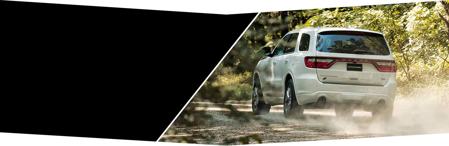 The 2022 Dodge Durango R/T drives on a dirt road with dust rising from its wheels.