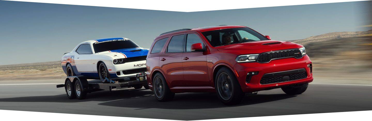 The 2022 Dodge Durango equipped with a 5.7L V8 towing a race car on a flatbed.