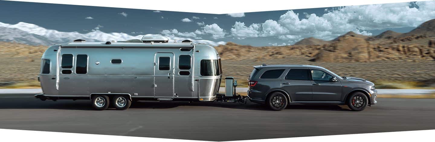 The 2022 Dodge Durango towing a travel trailer down a highway.