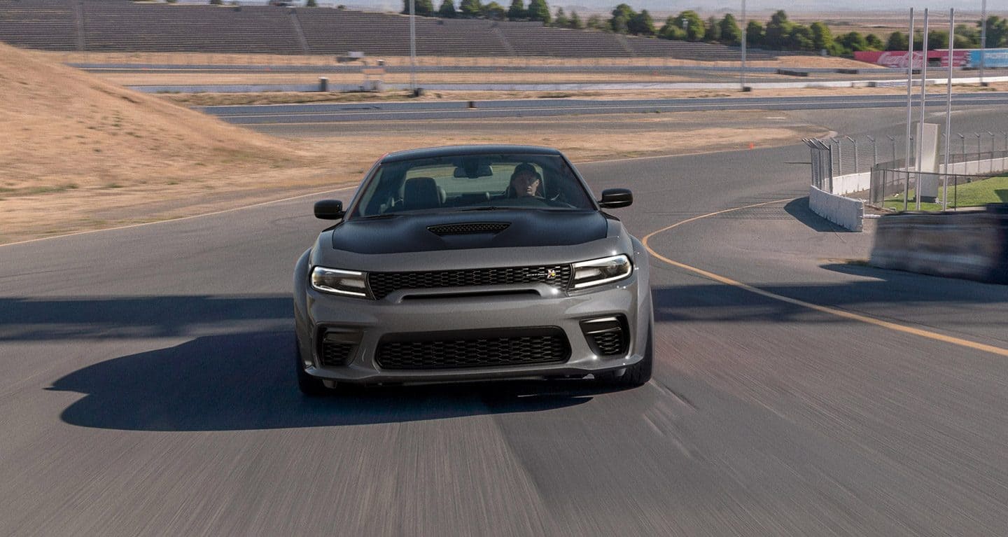 Display A gray 2023 Dodge Charger Scat Pack taking a curve on a track at a racing complex. 