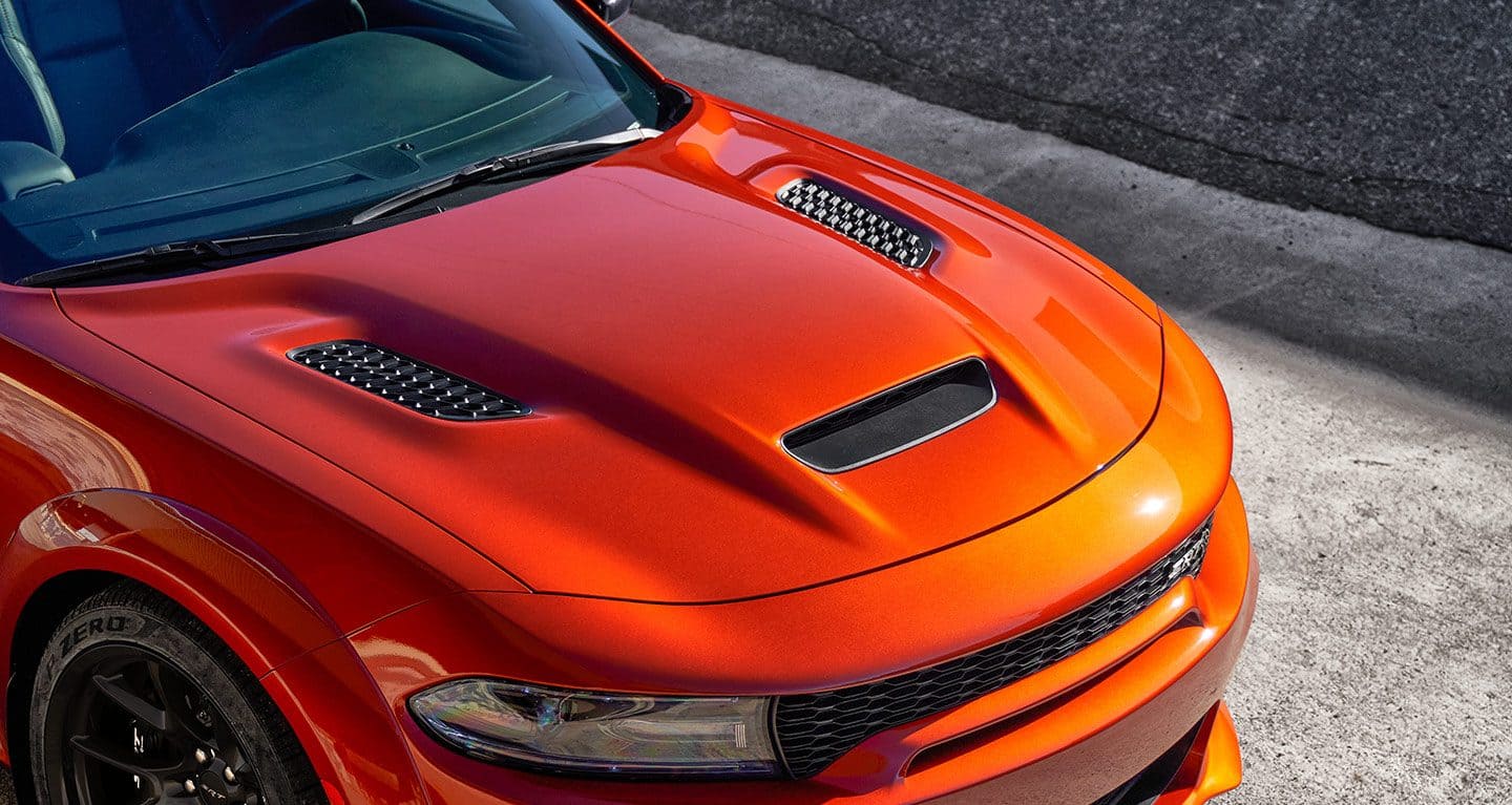 Display A raised angle of the hood on an orange 2023 Dodge Charger SRT Hellcat.