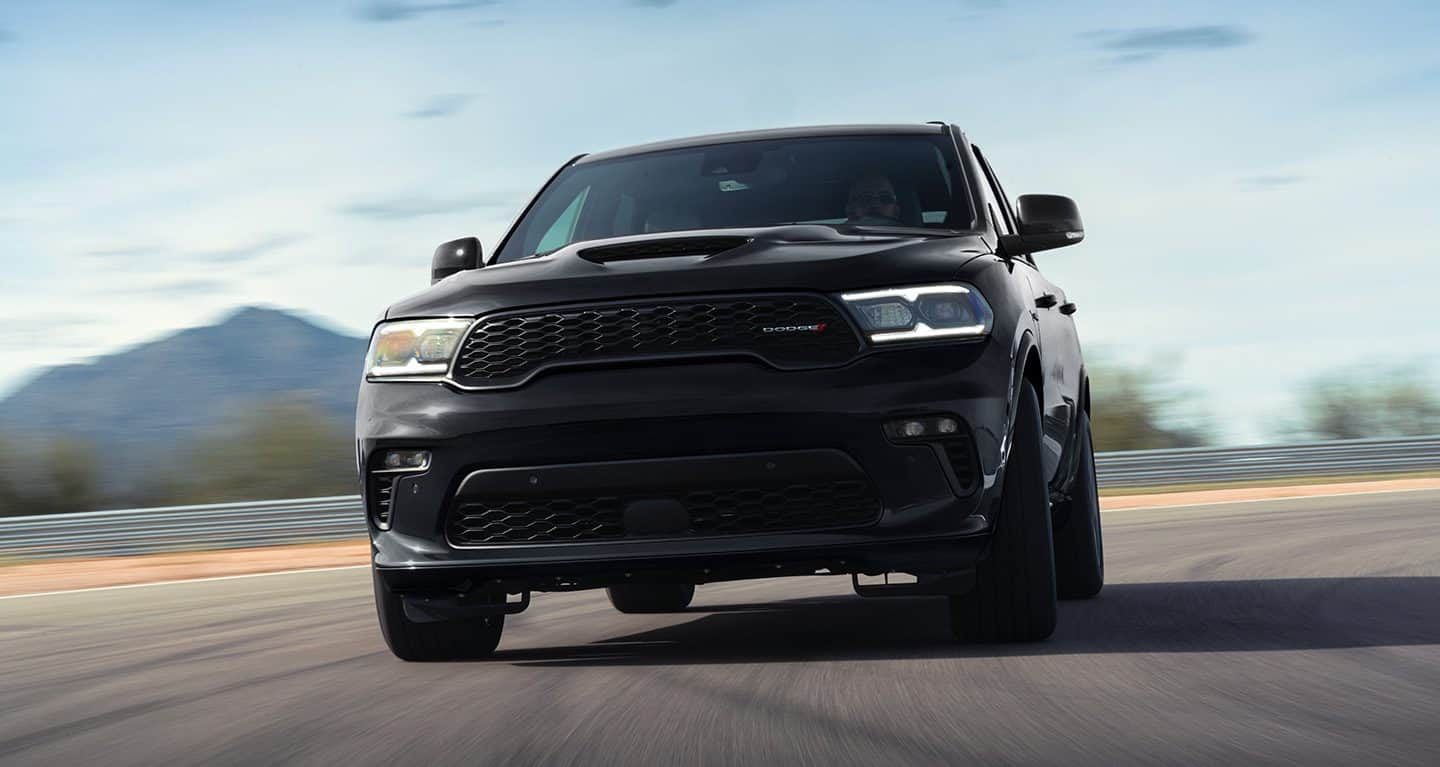 Display The 2023 Dodge Durango R/T being driven around a curve on a track, its grille and front fascia on display.