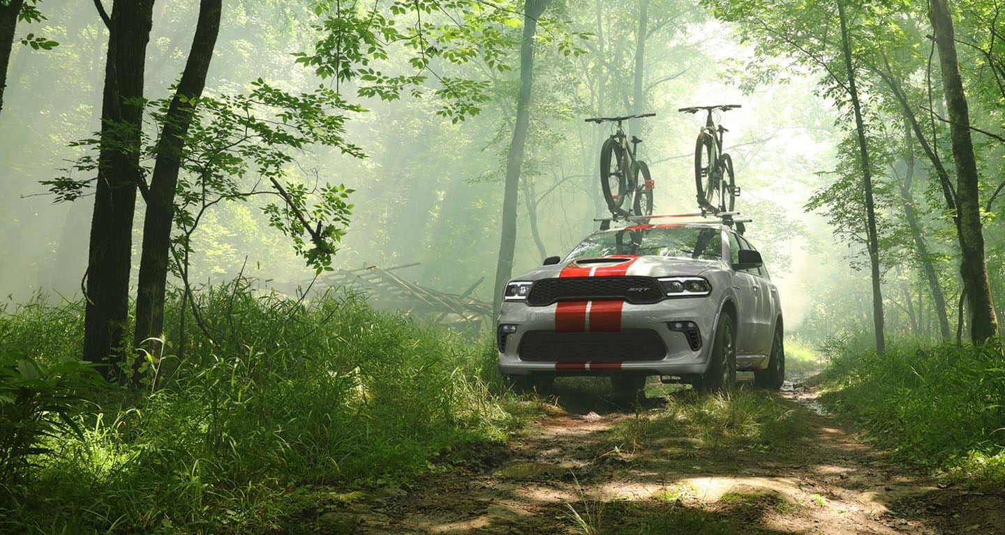 Display A 2023 Dodge Durango SRT 392 with two mountain bikes standing upright on the attached roof rack.