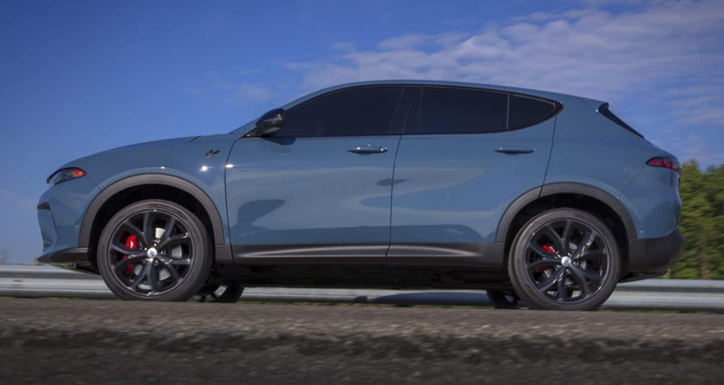 Display A profile of a light blue 2023 Dodge Hornet GT being driven down a track.