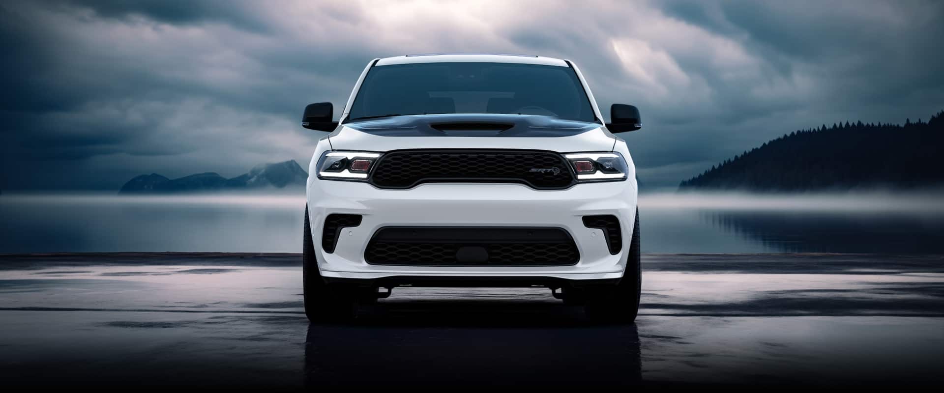A head-on angle of a white 2026 Dodge Durango SRT Hellcat with a lake and mountains in the background and storm clouds overhead.
