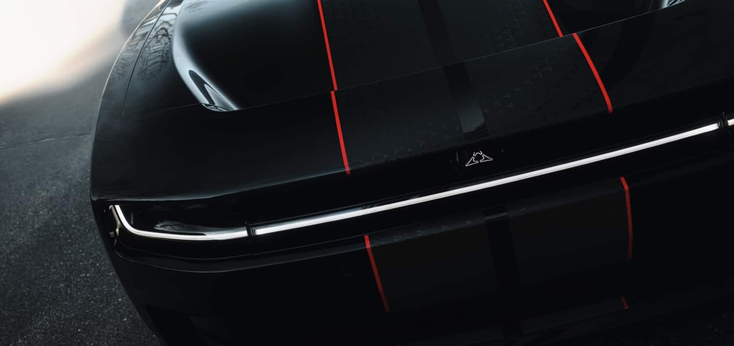 The hood and front end of a black  2027 Dodge Charger Scat Pack with dual black and red center stripes.