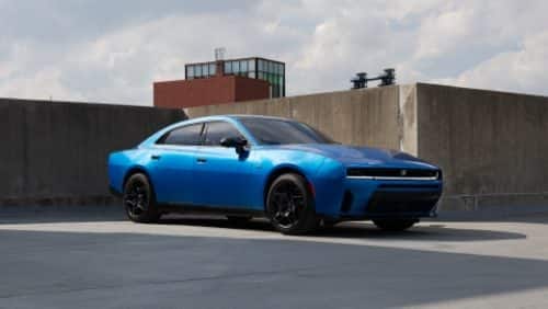 A blue 2027 Dodge Charger Scat Pack taking a curve on a country road.