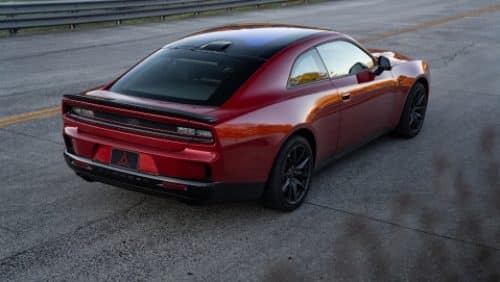 A red 2027 Dodge Charger Scat Pack with a black roof, shot from a rear profile.