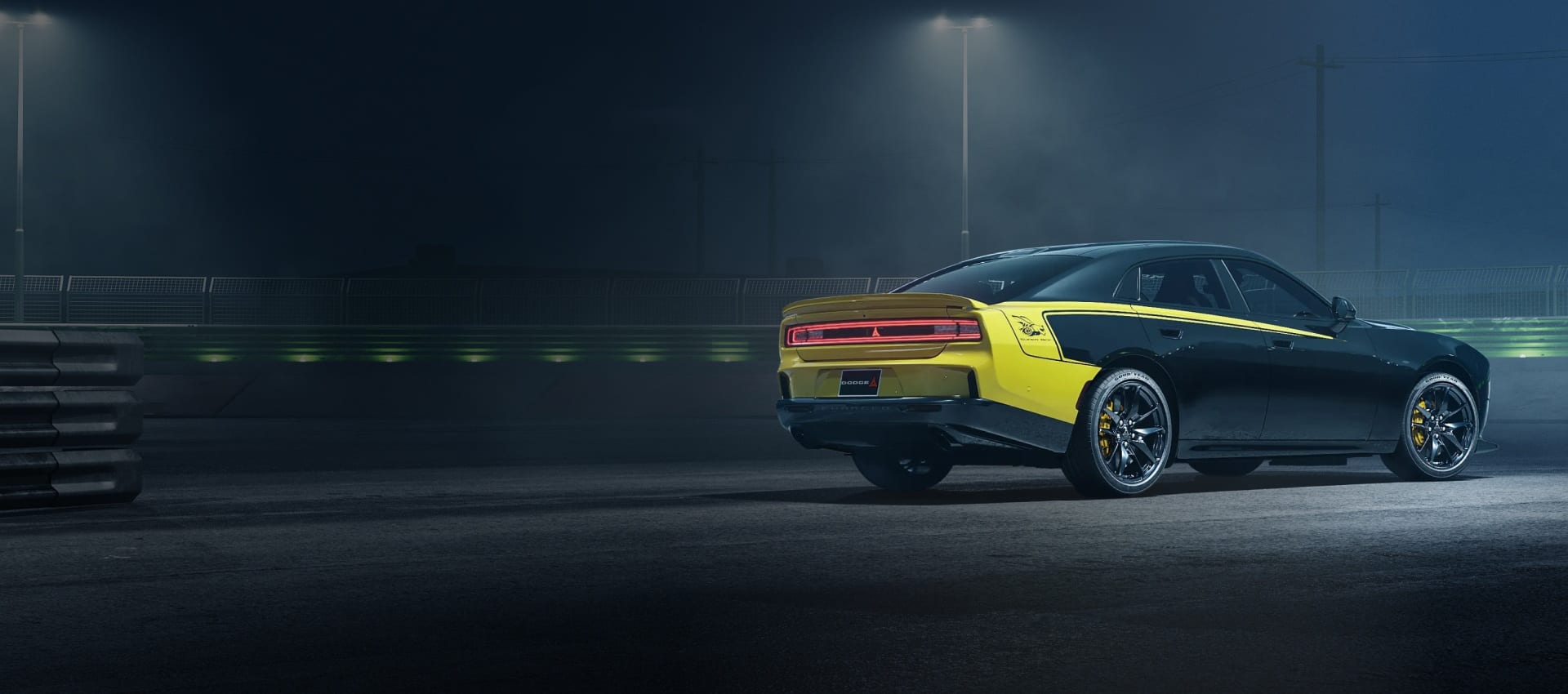 A 3/4 rear view of a Diamond Black 4-Door Super Bee Launch Edition parked on a track at night.