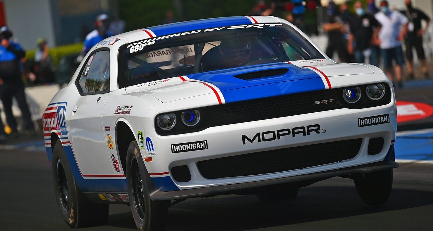 Display A blue and white Pro Stock Super Street Challenger at a racetrack.