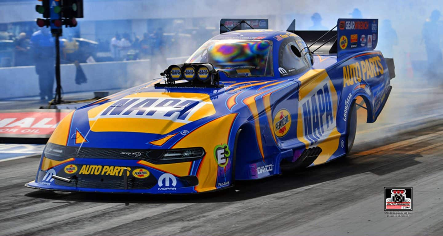 Display A blue and yellow Funny Car wreathed in smoke on a racetrack.