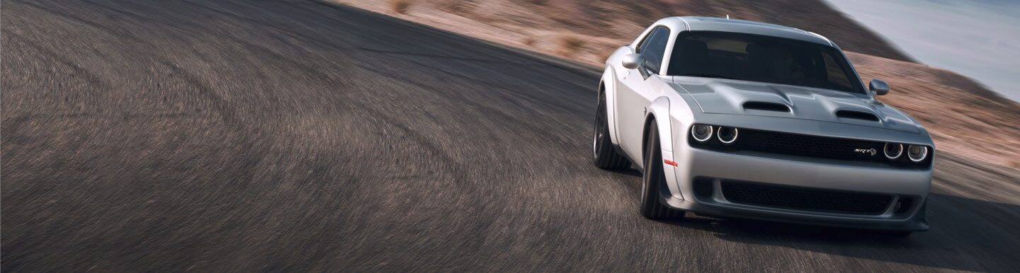 Three-quarter front profile view of a Dodge Challenger on a racetrack.