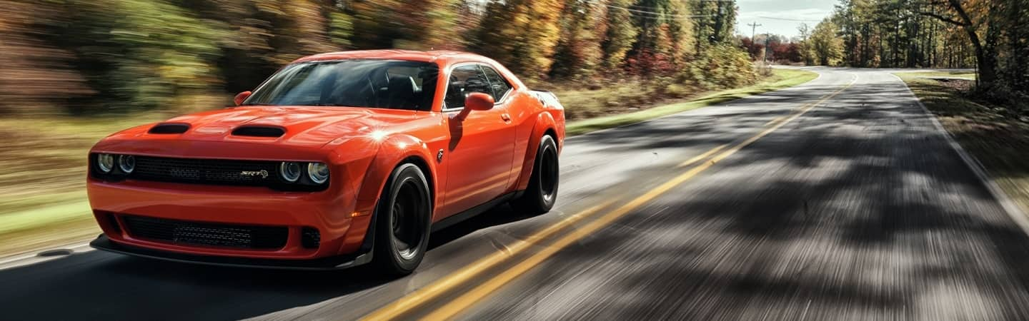 Three-quarter front profile view of a Dodge Challenger on a racetrack.