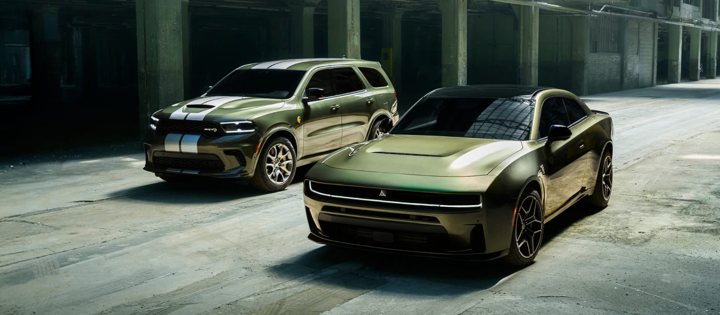 A green 2026 Dodge Durango SRT Hellcat Jailbreak with dual white center stripes and a green 2026 Dodge Charger Scat Pack Plus parked near each other.